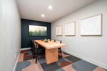 a conference room with a table and chairs and a painting on the wall